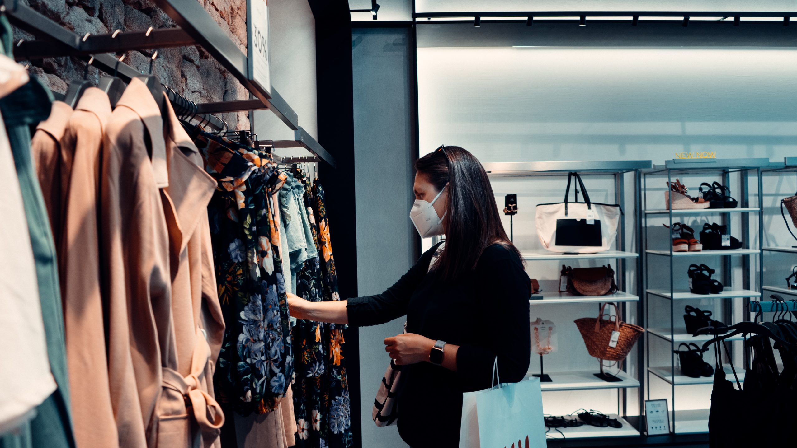 A woman shopping in a retail store wearing face mask following health and safey protocols after businesses reopen during COVID-19.