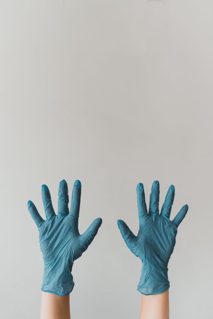 A pair of hands wearing protective gloves. Here are safety protocols you can following to reopen your business during COVID-19.